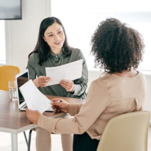 two people talking about paperwork in an office