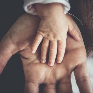 A small child's hand placed on an adult's hand
