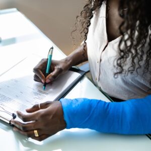 A woman with a hurt arm filling out paperwork
